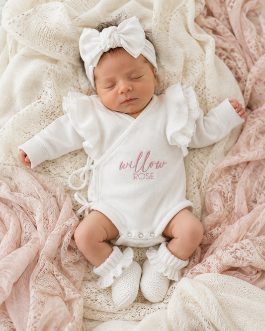 Newborn wearing personalized warm white Butterfly romper with bow and booties on textured pink blanket