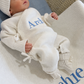 Newborn wearing the personalized Warm White Kimono long romper beside a matching embroidered knit blanket.