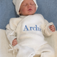 Sleeping newborn wearing the personalized Warm White Kimono long romper with bear-ear knit hat and classic booties, embroidered for their first Christmas.