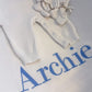 Close-up of name embroidery in blue thread on the Warm White personalized newborn Kimono set.