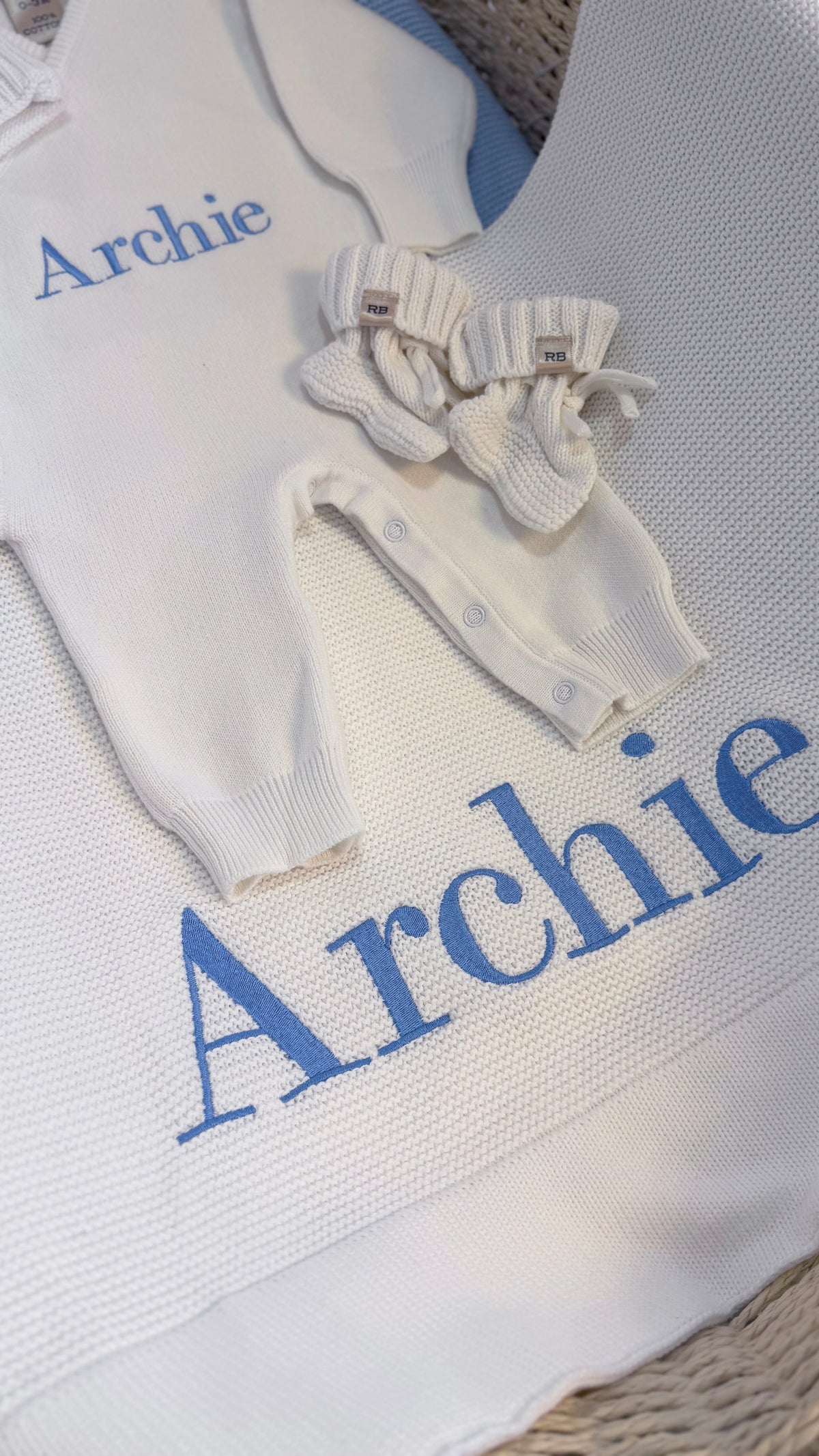 Close-up of name embroidery in blue thread on the Warm White personalized newborn Kimono set.