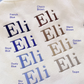 Blue embroidery thread color options displayed on Warm White knit fabric using the sample name Eli.