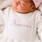 Newborn wearing personalized white and pink Ballerina romper with matching bow, close angle