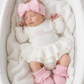 Newborn wearing personalized white and pink Ballerina romper, short style, with embroidered name and matching pink bow and booties