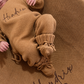 Baby wearing the Teddy Brown personalized kimono romper, bear-ear hat, and knit booties